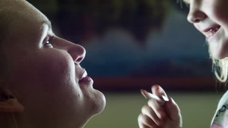 daughter applying lipstick to mother