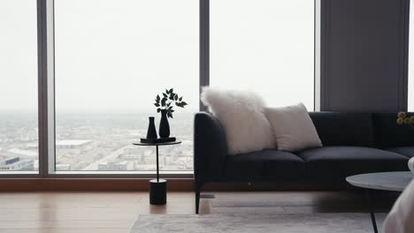 panning shot of a black couch with white pillows and a small side table in front of large windows in a high rise condo