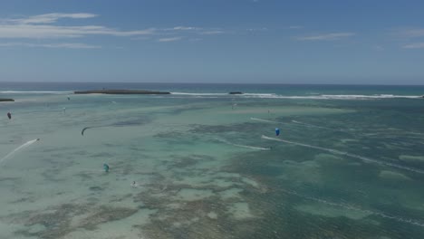 aerial shot captures several kitesurfers gliding across the shallow turquoise waters of sakalava bay, where coral reefs and sandbars create stunning natural textures near madagascar’s north coast