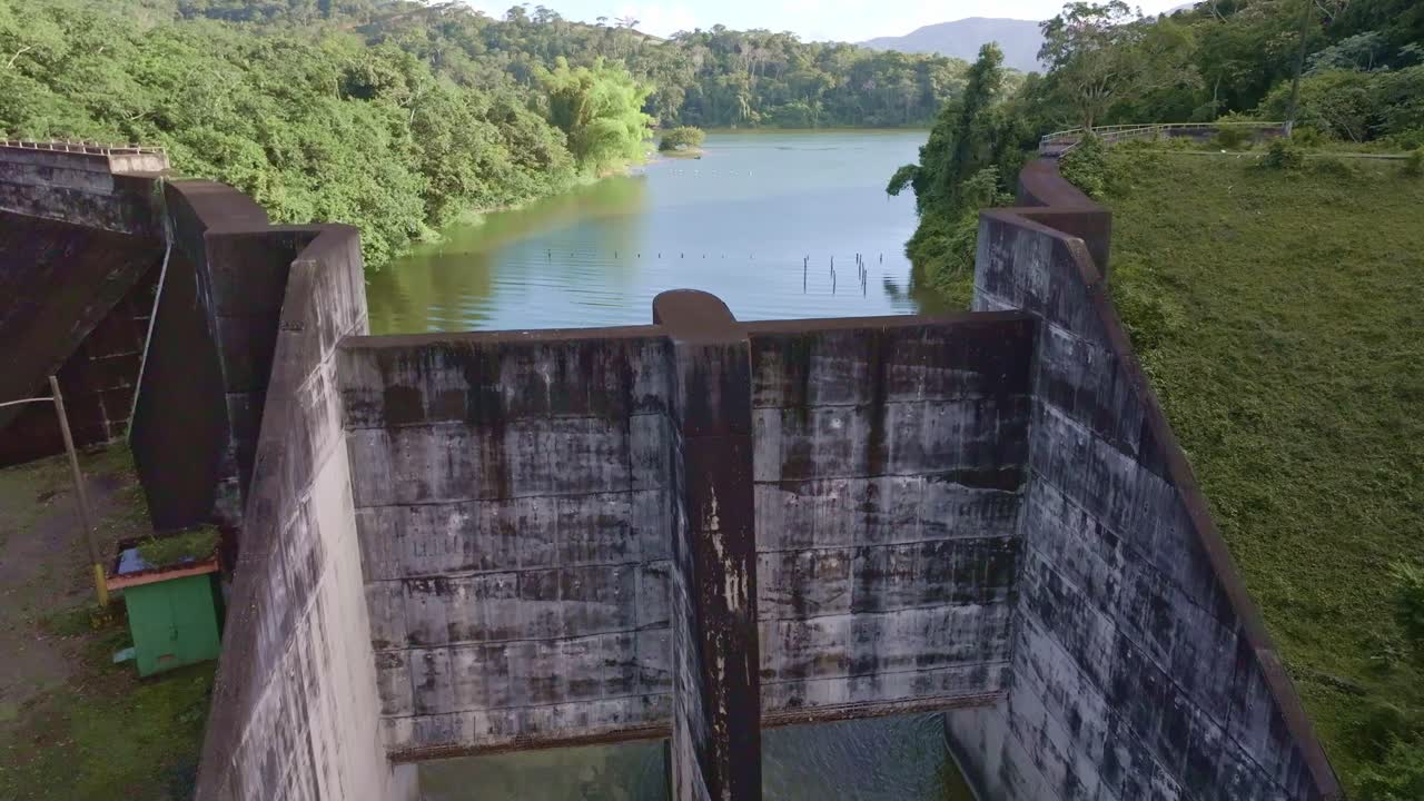 Hatillo Dam, concrete structure surrounded by lush greenery, Cotui in Dominican Republic. Aerial drone ascending