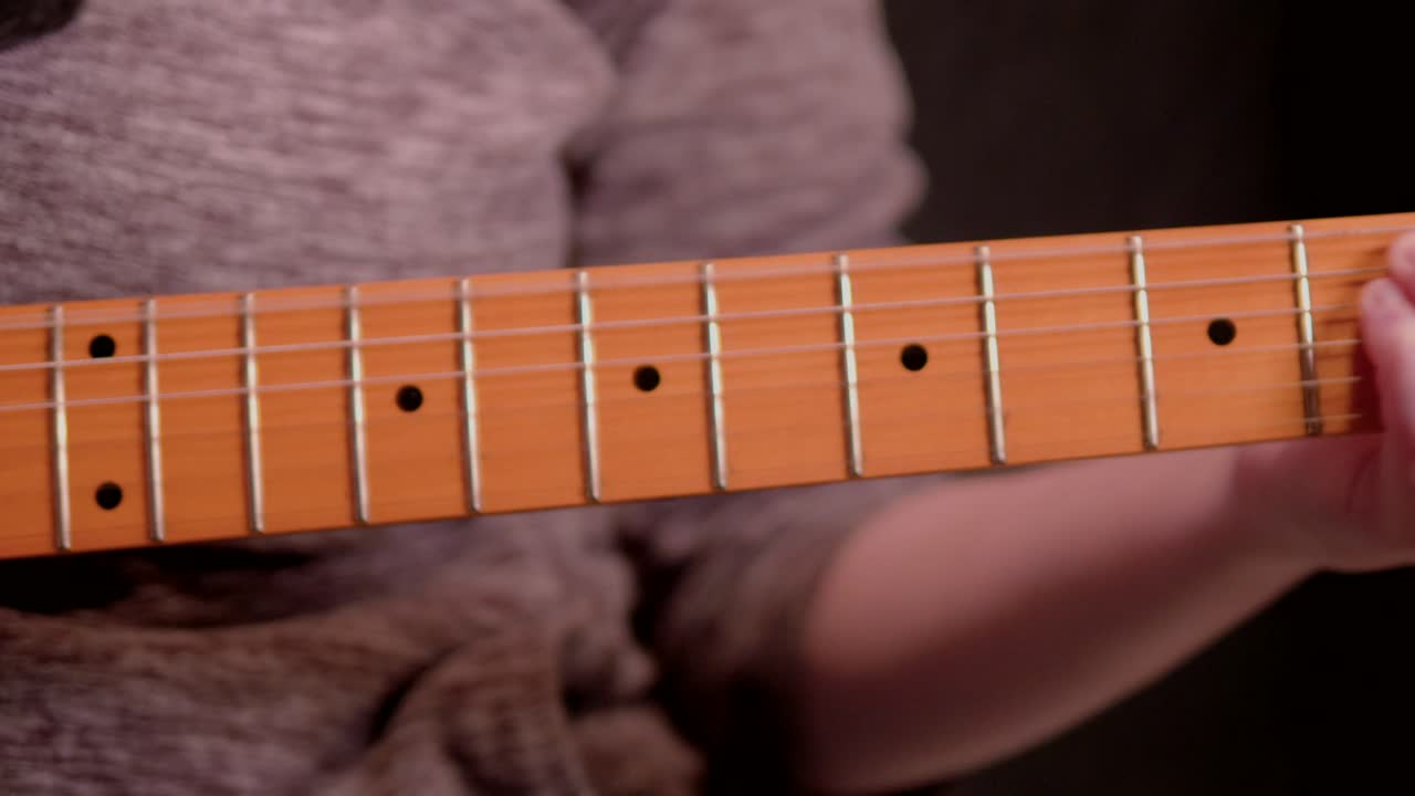 una mujer tocando la guitarra contra un fondo negro