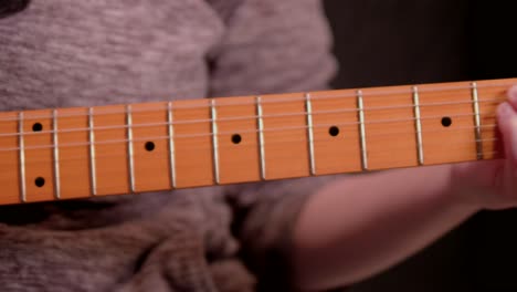 Una-Mujer-Tocando-La-Guitarra-Contra-Un-Fondo-Negro