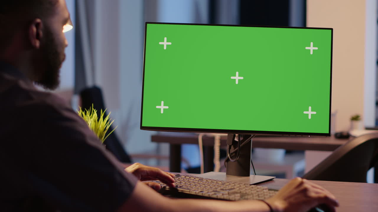 Man working on computer with green screen monitor