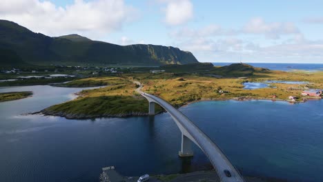 following a black car driving along the fredvang bridge in lofoten northern norway with the sea ocean water shimmering in light turquoise blue and green tones on a cloudy day in summer