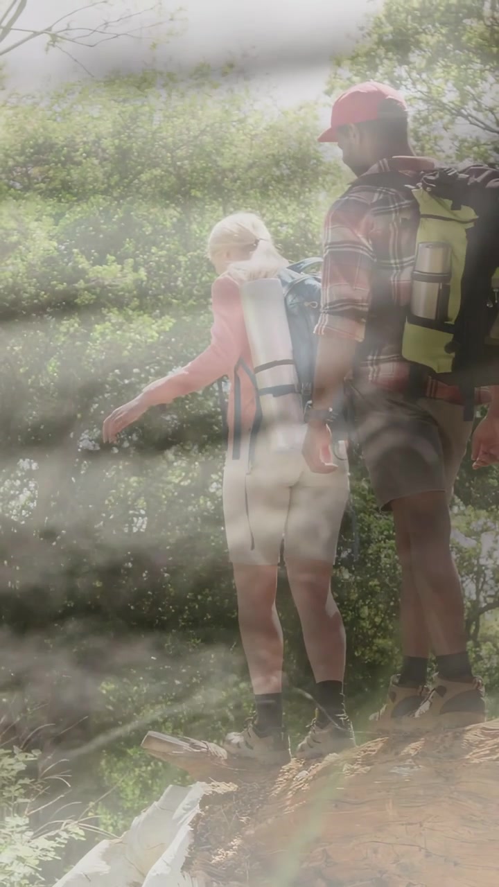 Video verticale: Due escursionisti che salgono su una sporgenza rocciosa, aggiustano l'appoggio, osservano il panorama, con foschia che copre le gambe