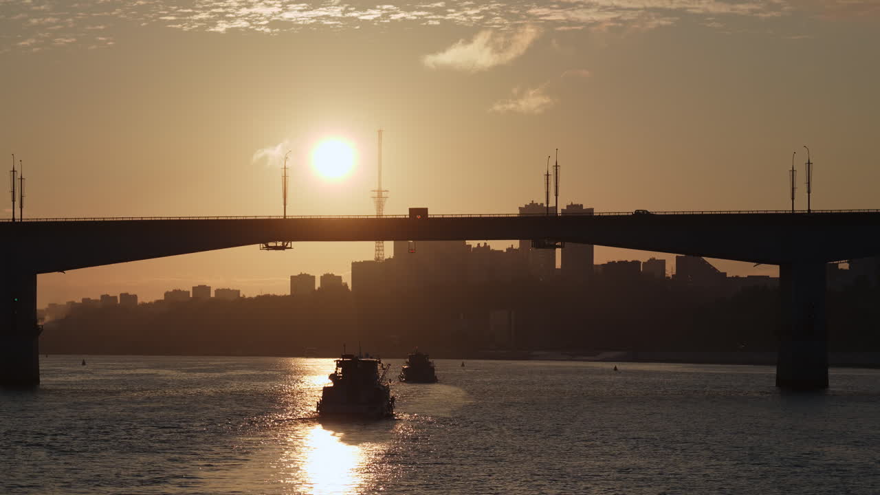 Sunset over a city river with bridge and boats