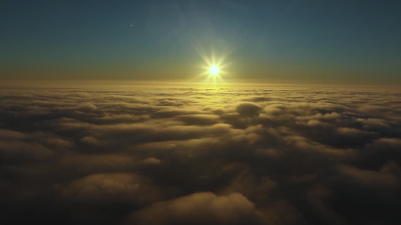 vista aérea elevándose por encima de las nubes mirando el sol bajo en el horizonte con rayos de luz