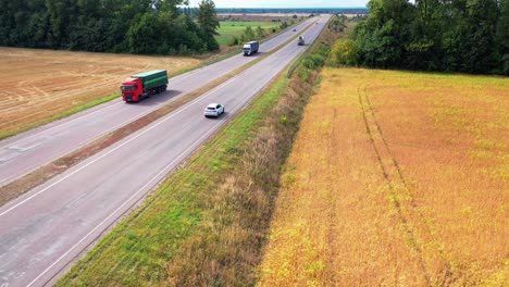 aerial view of a white car on highway. top view on the movement of cars on the road among fields and green trees background.