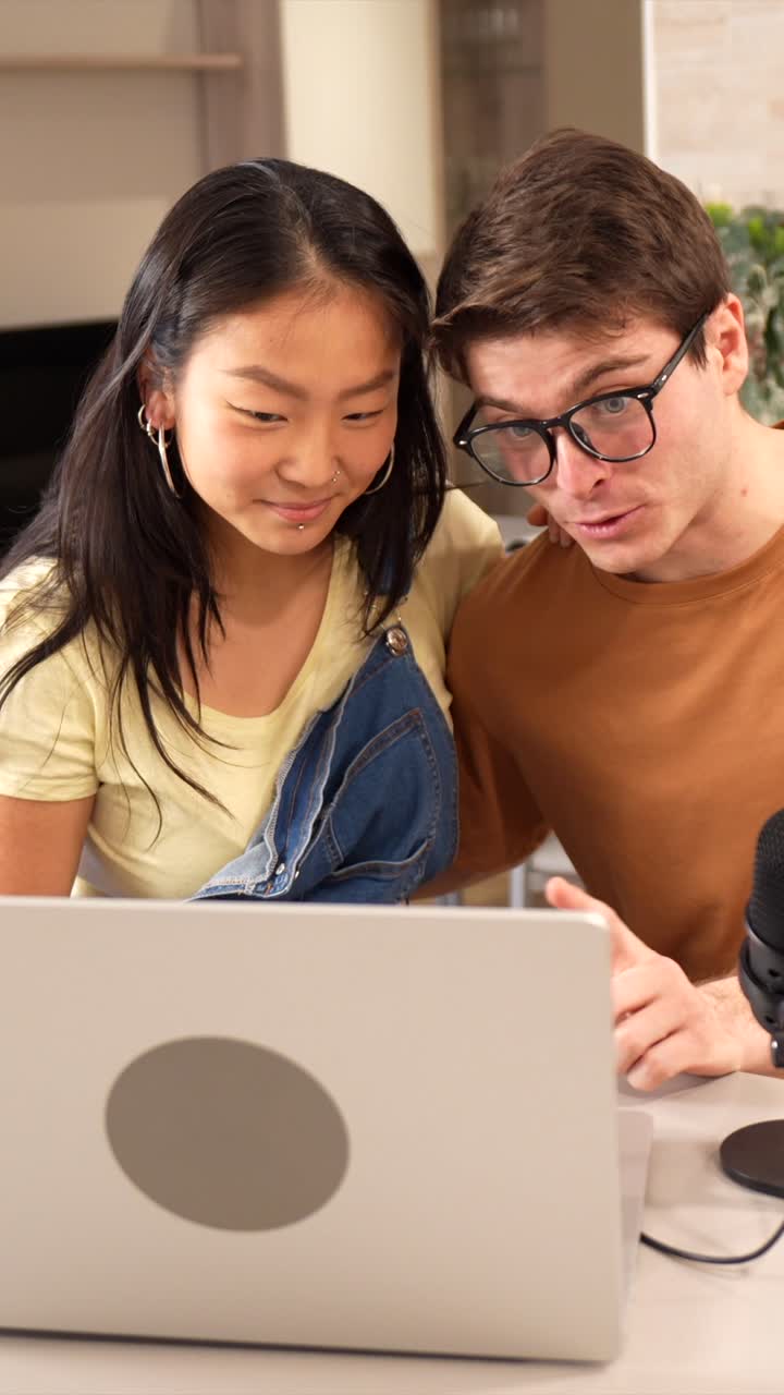 A couple recording a podcast using a laptop and microphone