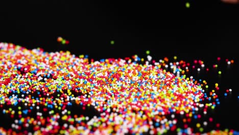 hand interacting with colorful sprinkles on surface