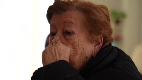 granny with wrinkles wearing a gold ring eating biscuits