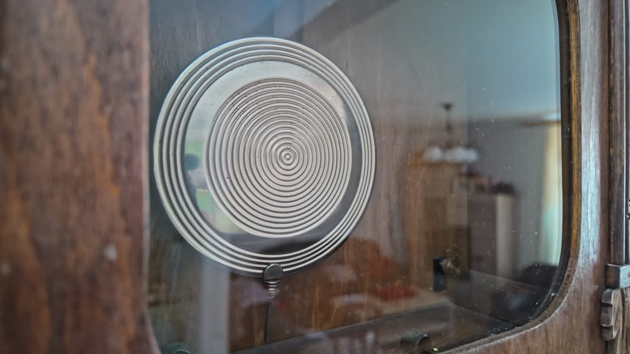 Close-up of an antique wall clock's pendulum in motion