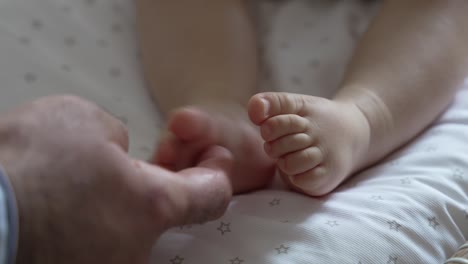 adult tickling baby's delicate feet. closeup