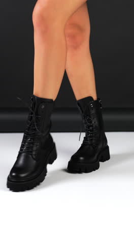 female model walks in black leather boots with tractor soles and laces. fashionable elegant footwear demonstration. vertical video