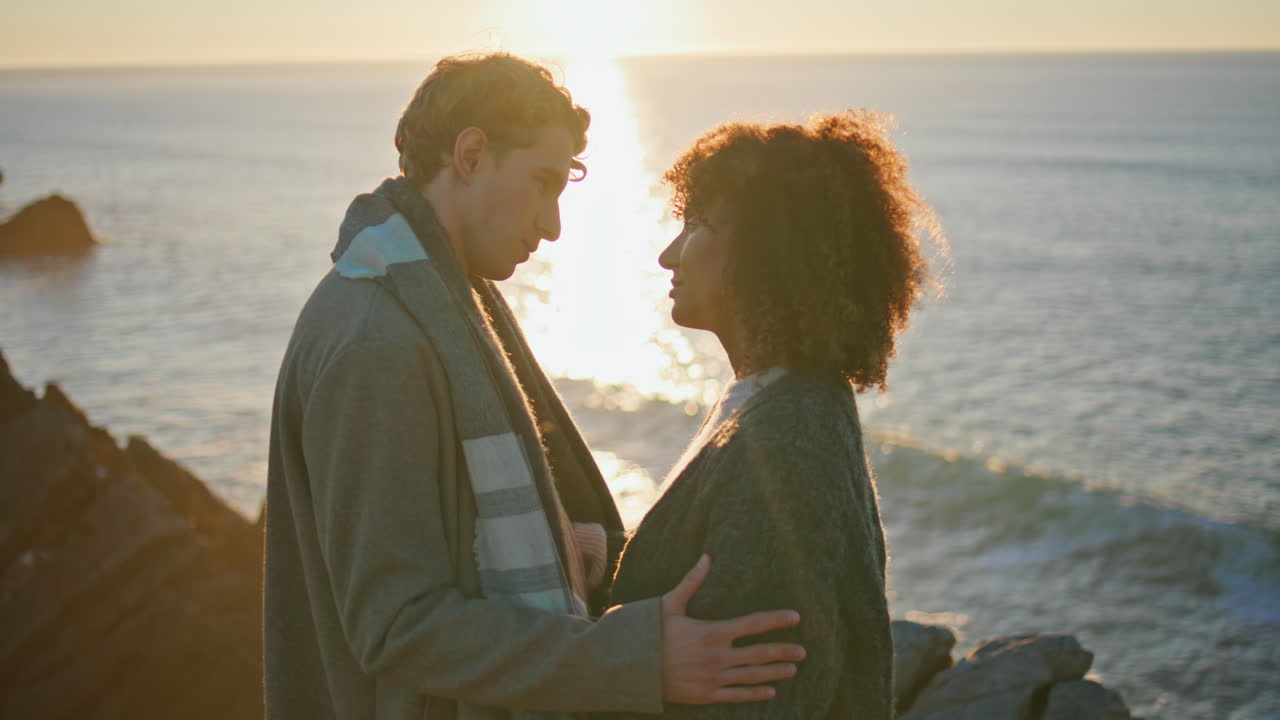 Multiracial lovers hugging together at evening sea closeup. Enamoured couple