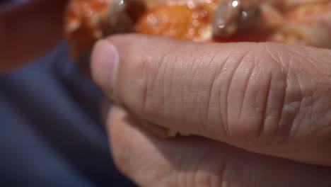 taking a bite of fresh sausage and tomato pizza - close up