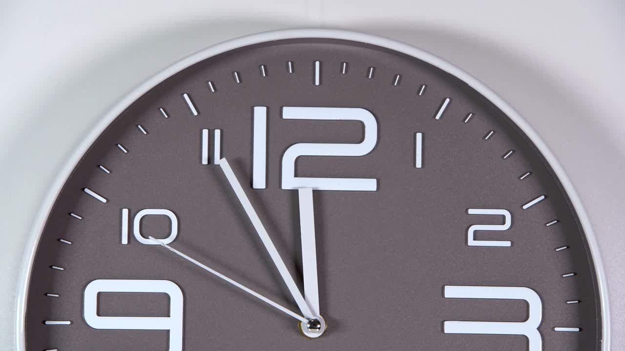 reloj de pared en un fondo gris. 23:55