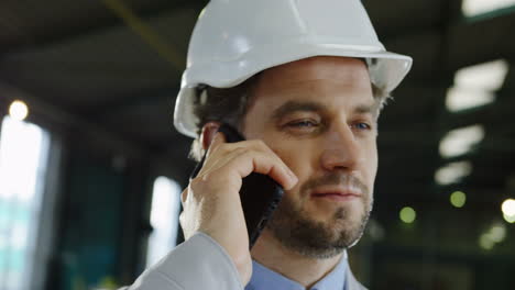 close-up view of engineer wearing a helmet and talking on the phone in a factory