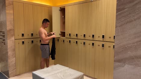 asian millennial man wearing shirt in luxurious changing room in a high end gym facility