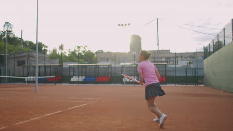 side view of a young caucasian woman playing tennis on a court returning a ball in slow motion