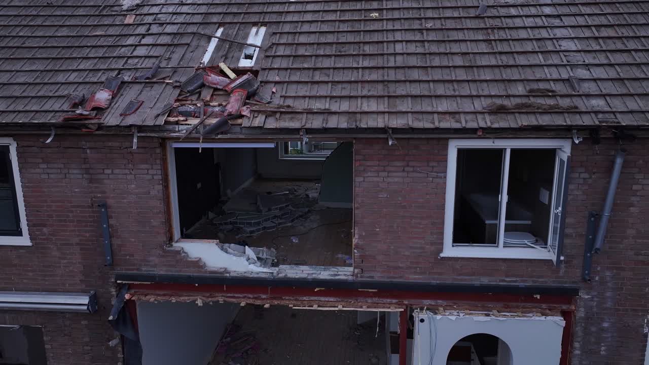 Aerial reveal of badly damaged buildings and rooftops being demolished