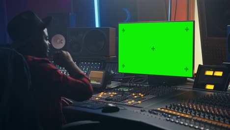 retrato de un elegante productor de ingenieros de audio masculino que trabaja en un estudio de grabación de música, utiliza una computadora de pantalla verde, un escritorio de control para crear una nueva canción. artista negro creativo baila mientras está sentado. sobre el hombro