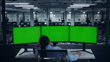 vista trasera de una mujer asiática aburrida trabajando con un simulacro de varios monitores de computadora en un centro de datos