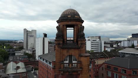 Aerial-drone-flight-around-London-Road-Fire-Station-in-Manchester-Piccadilly,-with-Piccadilly-Train-Station-in-the-background