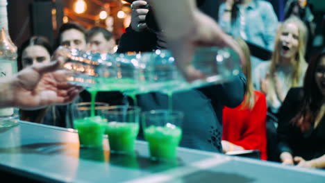 bartender masterly making three green cocktails at same time at nightclub