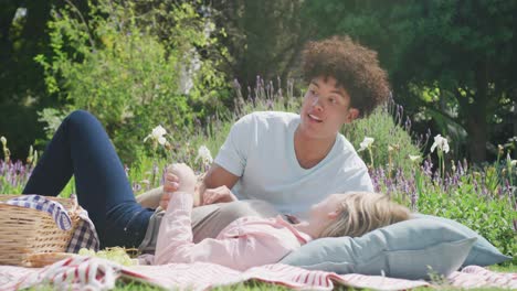 happy diverse couple having picnic in garden on sunny day