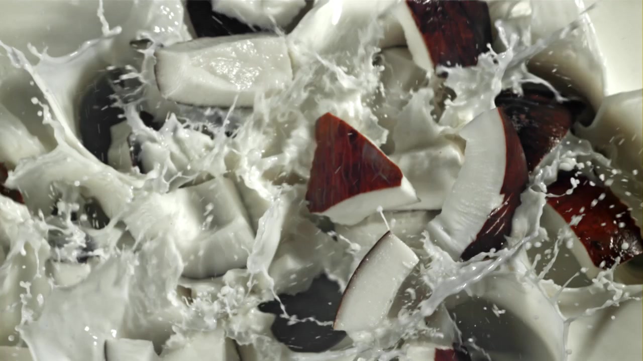 Fresh Coconut Pieces Splashing into Milk in Slow Motion