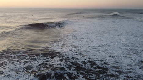 flying over waves in nazare, portugal at sunset