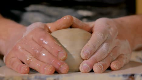 professional male potter working with clay on potter's wheel