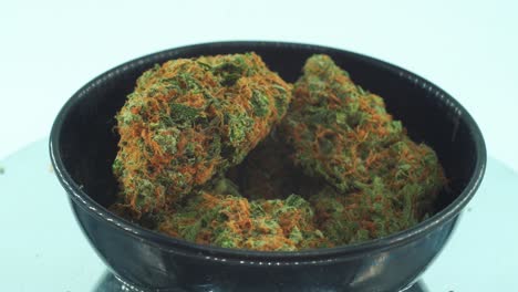 primer plano de una marihuana sativa flores de neblina superlimón, cepas de naranja, hierba verde, en un soporte giratorio reflectante de 360, en un llanto negro brillante, video de 4k en cámara lenta
