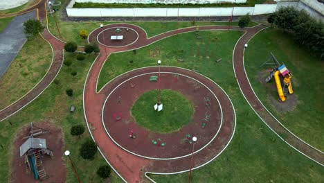 aerial tilt up tracking over a park with circle design and exercise machines, quality of life and health