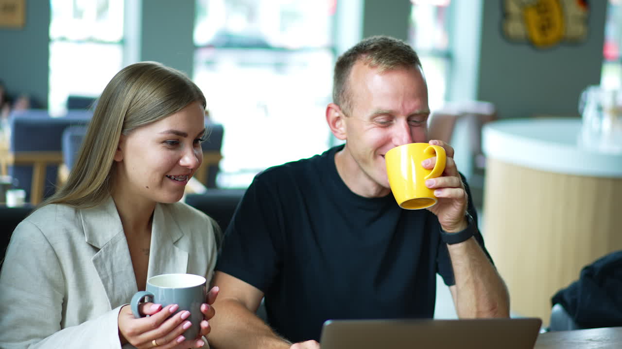 Young married couple enjoying coffee and good talk in a café. Spouses communicating and combining work and rest. Close up.