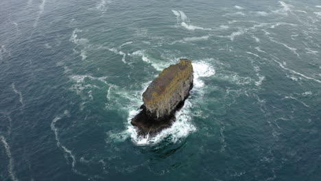 aerial view of a solitary sea stack in rough ocean waters