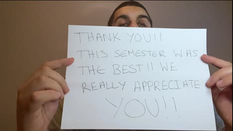 Young-University-Student-Holding-Up-Thank-You-Sign-During-Video-Lecture