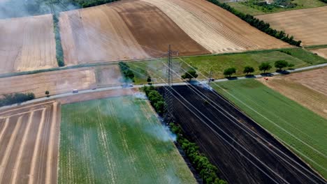 burnt wheat field with smoke - aerial drone shot