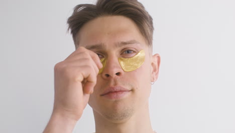 young man using and removing golden patch for the bags under the eyes