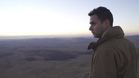 Hombre-Parado-En-La-Cima-De-Una-Montaña-Mirando-La-Vista-Del-Desierto