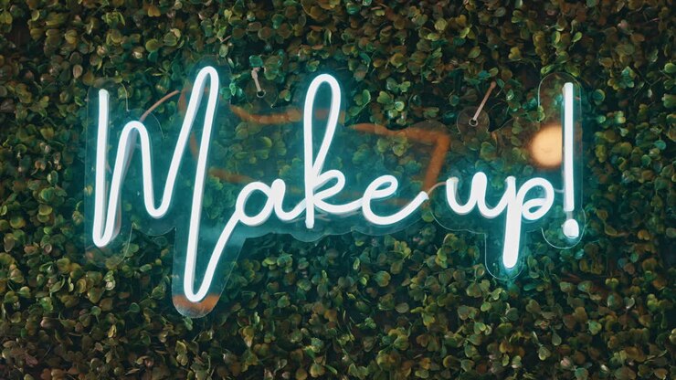 Glowing 'Make up!' Neon Sign on Green Artificial Leaf Wall