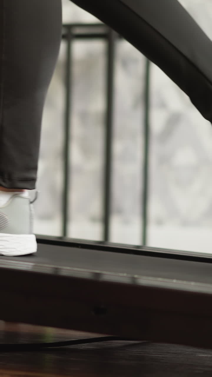 Woman walks and runs on treadmill at home closeup. Sportive lady with slim legs exercises on automatic trainer in domestic gym. Fitness training