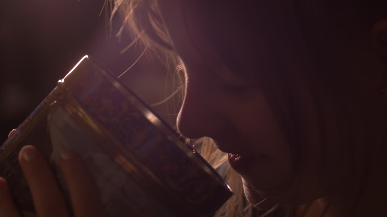 Young female child smells a metal box of cookies, joyful and smiling , close up