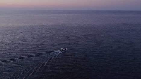 Vista-Aérea-Del-Barco-En-El-Mar-En-Calma-Con-Gente-Durante-La-Puesta-De-Sol,-Cefalu,-Sicilia,-Italia