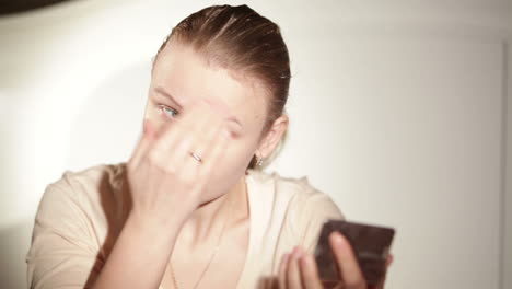 young woman is putting cosmetic cream on her face