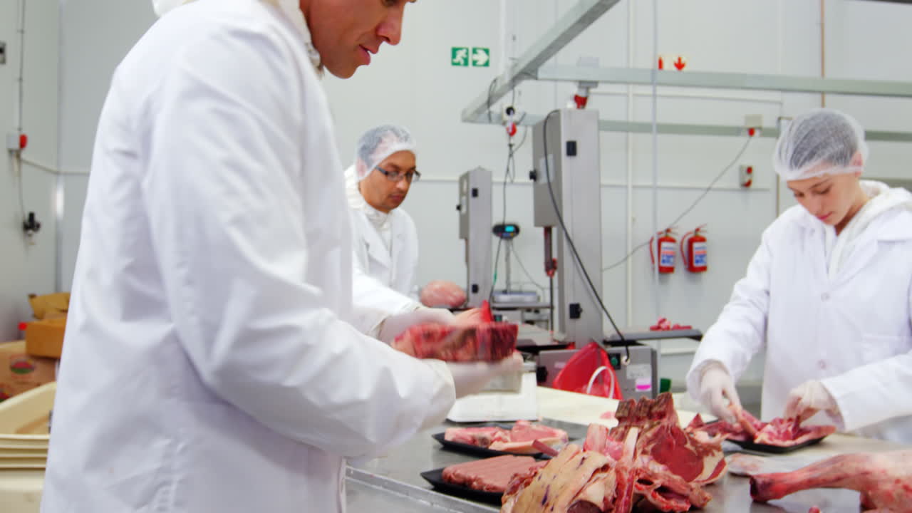 macellai che tagliano la carne e controllano il peso della carne nella fabbrica di carne