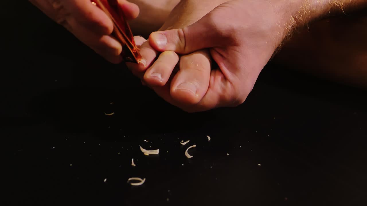 Detailed shot of personal toenail care in dark room, focus on hands and hygiene