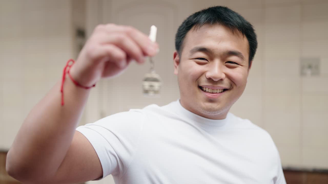 젊은 중국인 남자가 길거리에서 새로운 집의 열를 자신 있게 웃고 있습니다.