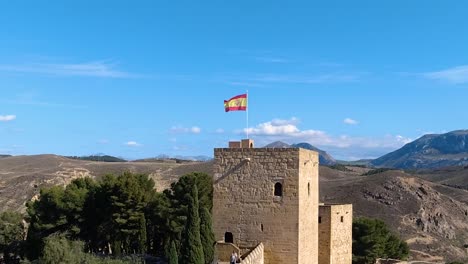 antequera alcazaba castle with spanish flag waving with mountains in background